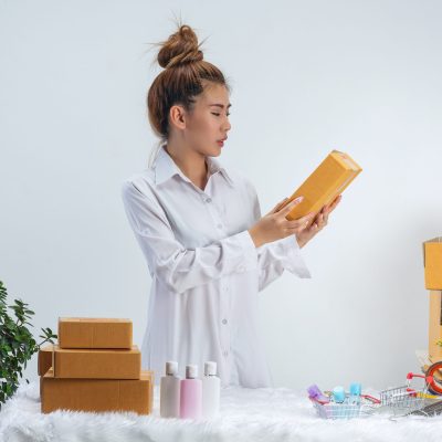 A business woman is working online and traing to reply customer  at home office packaging on background.